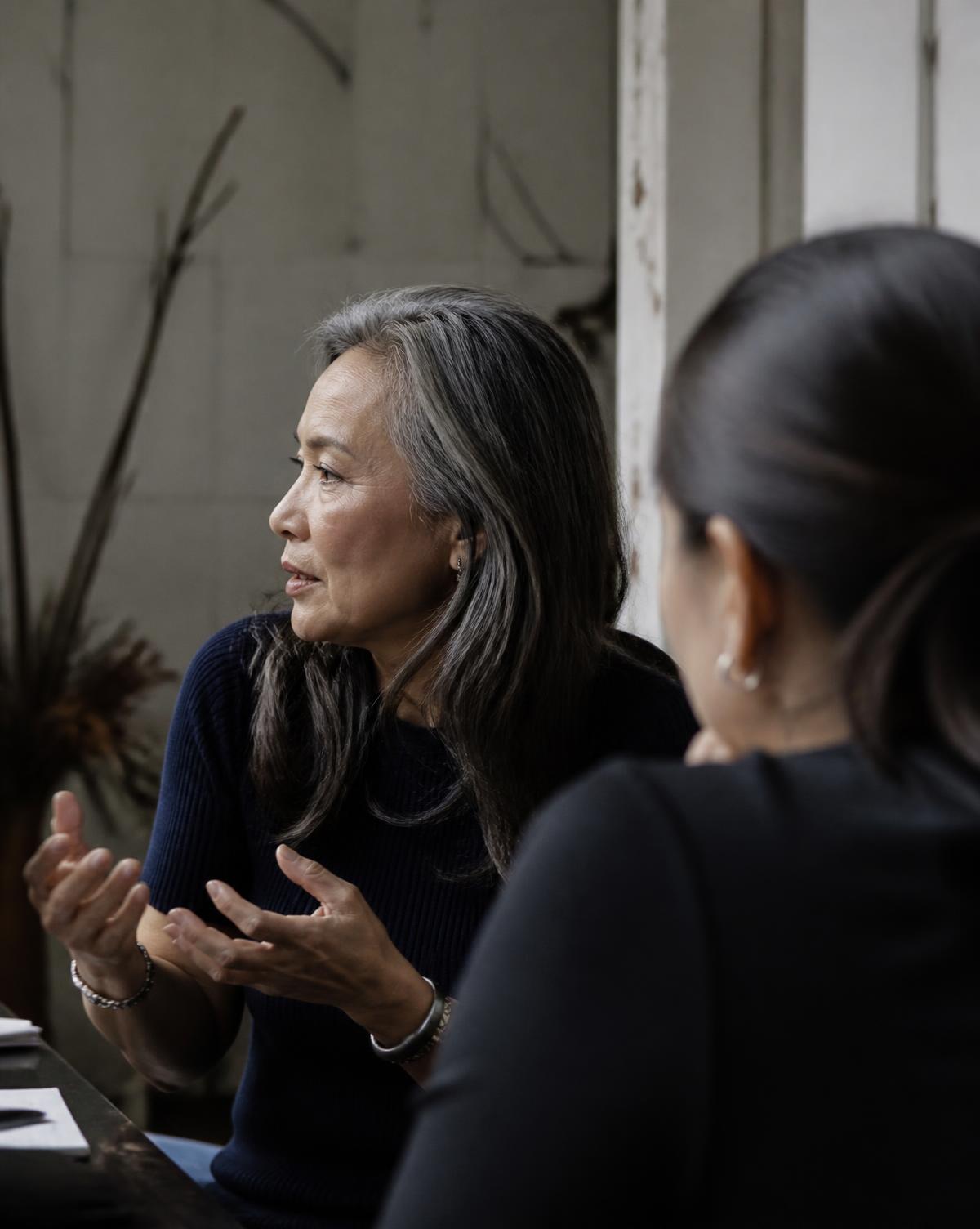 Two women in a focused conversation, with one speaking thoughtfully in profile.